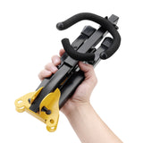 A hand holding a black and yellow saxophone stand that has been folded up in to a compact size and shape