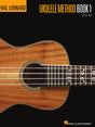 The image shows the cover of "Hal Leonard Ukulele Method Book 1" by Lil' Rev. It features a close-up of a wooden ukulele with decorative rope binding, an ornate sound hole rosette, part of the fretboard with fret markers, and four strings. Musical notation symbols appear over the fretboard. The background is black with orange-yellow text, displaying the Hal Leonard logo at the top and bottom. This is an instructional book for beginning ukulele players.