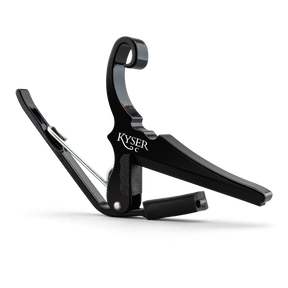 The image shows a Kyser Quick-Change guitar capo with a black finish and spring-loaded, curved arms. The "KYSER" branding is visible on its C-shaped clamp, designed for quick release and easy movement along the fretboard. This popular capo raises pitch by clamping all strings, allowing guitarists to change keys without new fingerings. Kyser capos are known for durability, reliable intonation, and protecting guitar necks.
