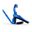 The image shows a bright blue Kyser guitar capo with a spring-loaded, curved clamp design. The "KYSER" name is visible on the metal body. It has black rubber padding to protect the guitar neck and strings while ensuring a secure grip. This quick-change capo is popular for easy one-handed use during performances, offering durability and an attractive anodized finish.