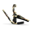 The image shows a KYSER spring-loaded guitar capo with a camouflage pattern in green, brown, and tan. It features a curved metal frame, a padded bar to press the strings, and a strap attachment point. This quick, one-handed capo evenly clamps all strings for clean sound and is popular among guitarists for easy use during performances.