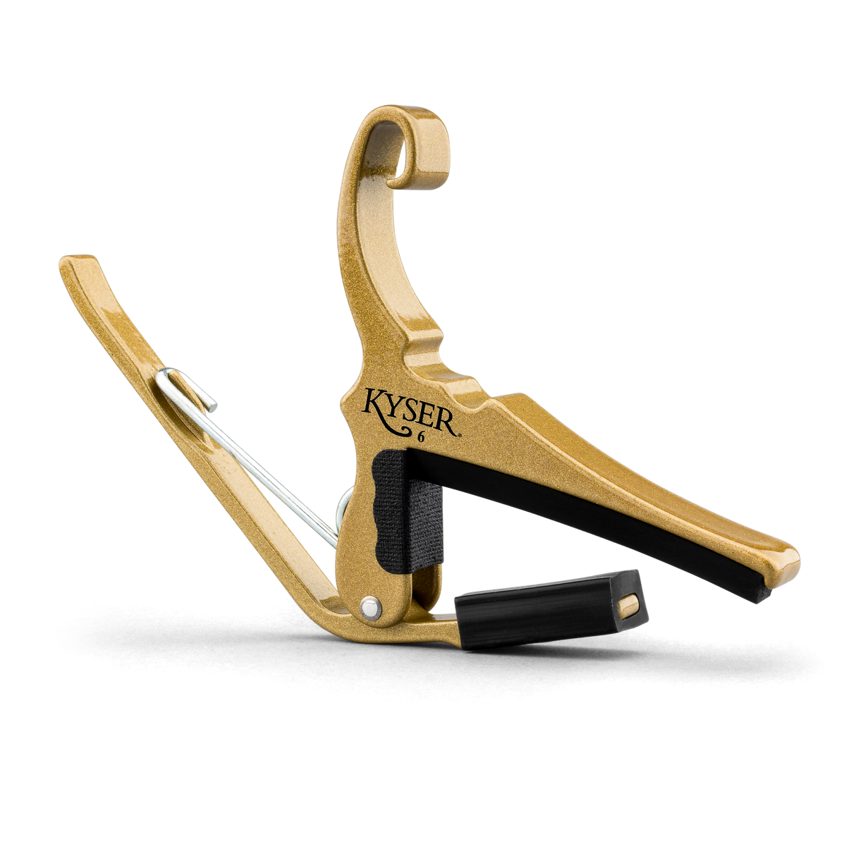 The image shows a Kyser brand guitar capo with a gold/brass metal frame and black padded bar. It features a curved hook shape, spring-loaded mechanism for one-handed use, and black padding to protect the guitar neck. Capos clamp all strings at a fret to raise pitch. Kyser capos are popular for their quick-change design and reliable grip.