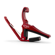 The image shows a Kyser spring-loaded, trigger-style guitar capo with a red anodized aluminum finish. It has black rubber padding to protect the guitar strings and neck while providing a secure grip. This popular accessory allows quick key changes by clamping all strings at any fret. Its curved design fits the guitar neck for even pressure, and the spring mechanism enables easy one-handed use.
