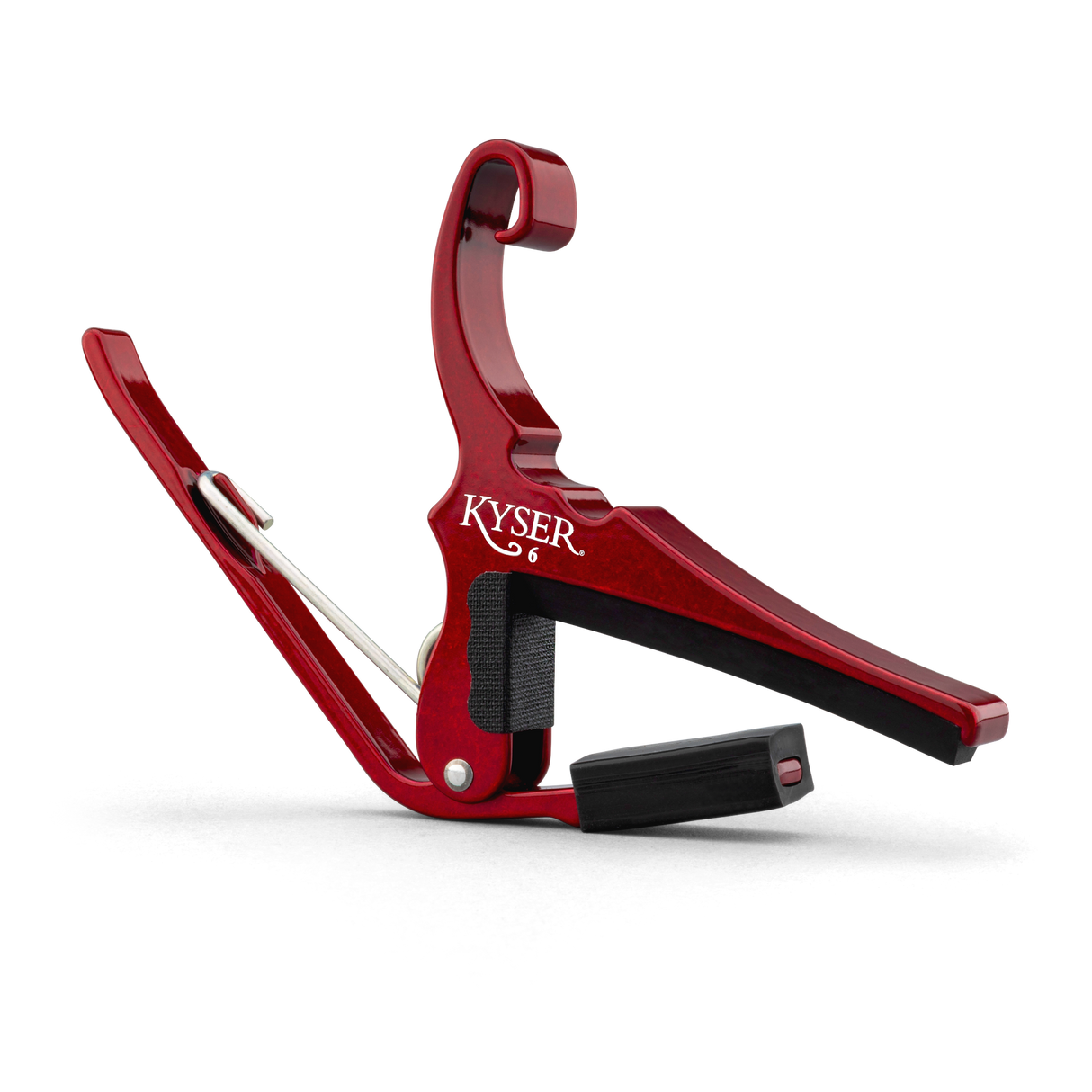 The image shows a Kyser spring-loaded, trigger-style guitar capo with a red anodized aluminum finish. It has black rubber padding to protect the guitar strings and neck while providing a secure grip. This popular accessory allows quick key changes by clamping all strings at any fret. Its curved design fits the guitar neck for even pressure, and the spring mechanism enables easy one-handed use.