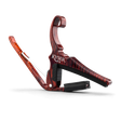 The image shows a Kyser guitar capo with a reddish-brown wood grain finish resembling rosewood. It features a spring-loaded clamp and curved handle for one-handed use, a black rubber pad that presses the strings, and a black fabric strap for secure attachment. This quick-change style capo raises the pitch by clamping the fretboard, allowing guitarists to easily change keys while using familiar chord shapes.