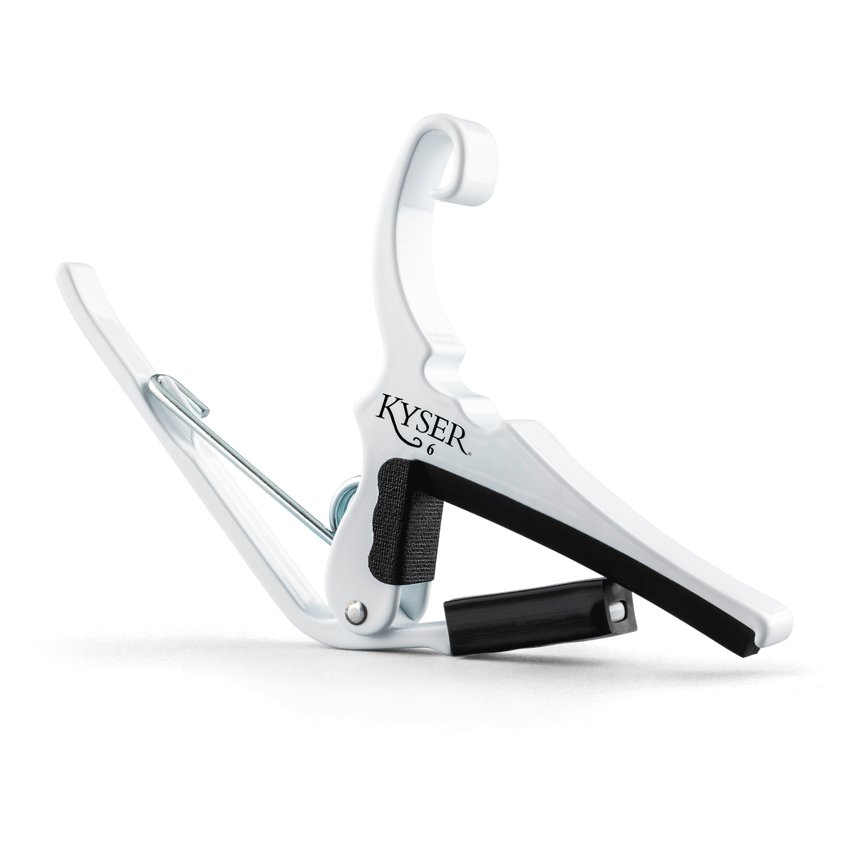 The image shows a white Kyser Quick-Change Capo, a spring-loaded clamp for guitar fretboards. It features a curved design with black rubber padding to protect the neck and frets. The capo allows easy one-handed use, enabling guitarists to change keys quickly while playing. Kyser is a popular brand known for its reliable, fast placement capo models favored by many guitarists.