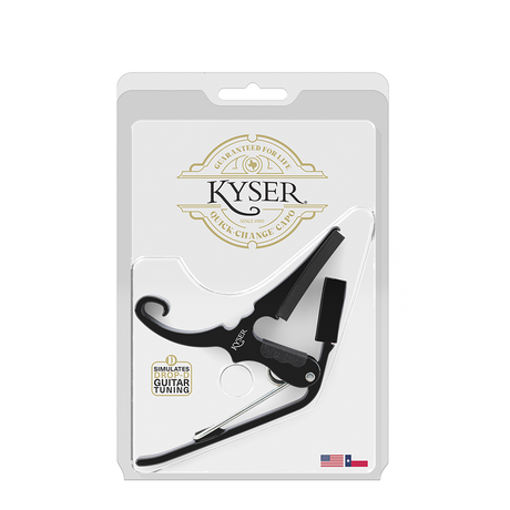 The image shows a Kyser Quick-Change Guitar Capo in its retail blister packaging. It features a curved black spring-loaded body with metal parts and the classic Kyser one-handed quick-change design. The packaging displays the Kyser logo, "Guaranteed for Life" branding, "Simulates Drop-D Guitar Tuning," and an American flag indicating it is made in the USA.