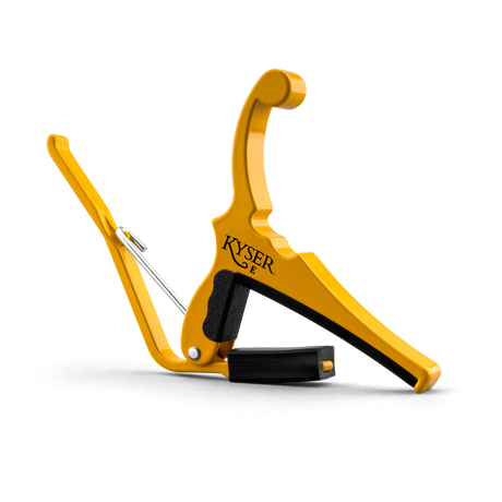 The image shows a Kyser Quick-Change guitar capo, featuring a bright yellow/gold spring-loaded design. It has black rubber padding to protect the guitar neck, even pressure across strings, and the "KYSER" logo. Made of durable metal, it enables quick one-handed use. This popular capo is favored by guitarists for easily changing keys while keeping chord shapes, widely used across many music genres.