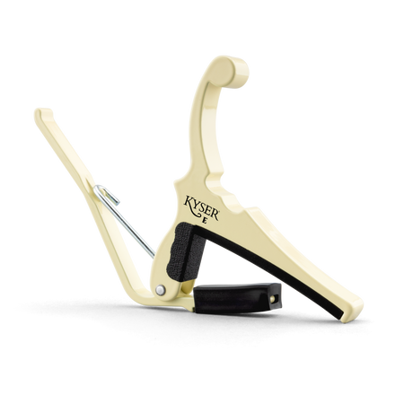 The image shows a Kyser Quick-Change guitar capo with a cream-colored metal body. It features a spring-loaded, lever-style mechanism for easy one-handed use, black rubber padding to protect the guitar, and a curved design to fit the neck. This accessory clamps across the fretboard to raise pitch, enabling guitarists to play in different keys while using familiar chord shapes.