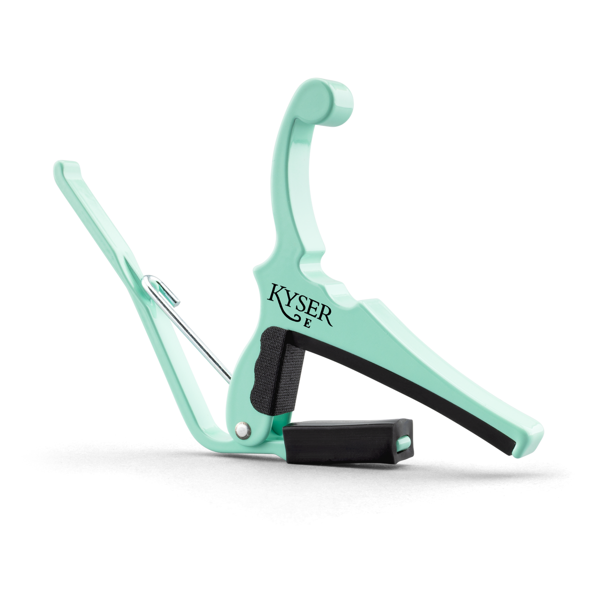 The image shows a Kyser guitar capo in a mint green finish. This spring-loaded capo has a curved metal frame, black rubber padding to protect the strings and fretboard, and an ergonomic handle for easy one-handed use. Kyser is known for quick-change capos popular with acoustic and electric guitarists for fast fret adjustments during performances.