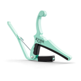 The image shows a Kyser guitar capo in a mint green finish. This spring-loaded capo has a curved metal frame, black rubber padding to protect the strings and fretboard, and an ergonomic handle for easy one-handed use. Kyser is known for quick-change capos popular with acoustic and electric guitarists for fast fret adjustments during performances.