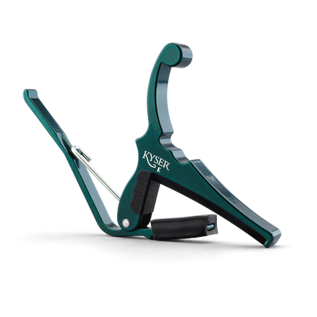 The image shows a Kyser spring-loaded guitar capo with a green anodized aluminum finish. It features a curved clamp, black rubber padding to protect the guitar neck, and a quick-change design for one-handed use. The Kyser logo is visible on the body. This durable, lightweight capo is popular for easily shifting keys on acoustic and electric guitars.