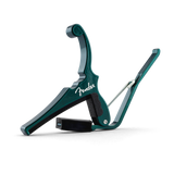 The image shows a teal Fender spring-loaded trigger capo with a white Fender logo. It features a padded black bar that clamps across the guitar fretboard and a curved handle for easy one-handed use. This sleek capo allows guitarists to change keys quickly while maintaining familiar chord shapes, combining functionality with Fender’s classic design, and is popular for acoustic playing.