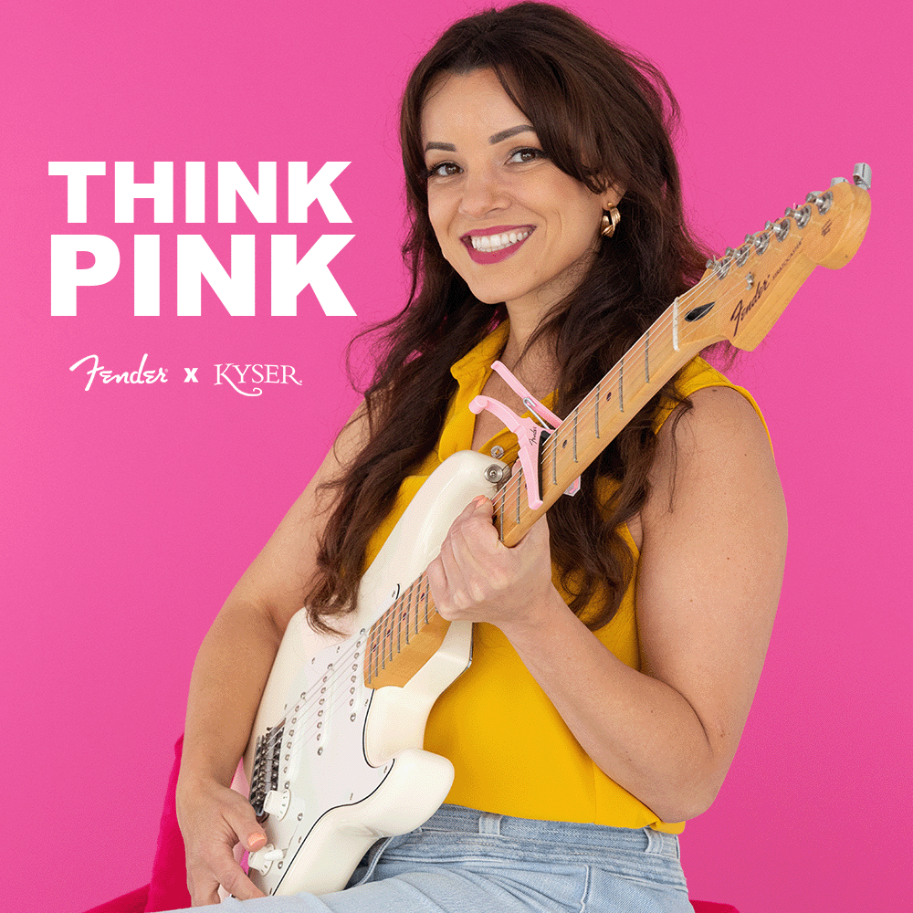 The image shows a classic Fender Stratocaster electric guitar with a white body, maple neck, three single-coil pickups, white pickguard, and chrome hardware. It is featured in the "THINK PINK" campaign, a collaboration between Fender and KYSER, set against a vibrant pink background, likely promoting a special edition or awareness initiative. The Stratocaster is a legendary, versatile guitar used across many music genres.