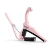 The image shows a pink Kyser guitar capo with a spring-loaded, curved handle for one-handed use. It features black rubber padding to protect the guitar neck, the "KYSER" logo on the clamp, and a sleek, ergonomic design typical of Kyser’s Quick-Change series. This capo, suitable for acoustic and electric guitars, allows players to change pitch easily while adding a stylish, personalized touch.