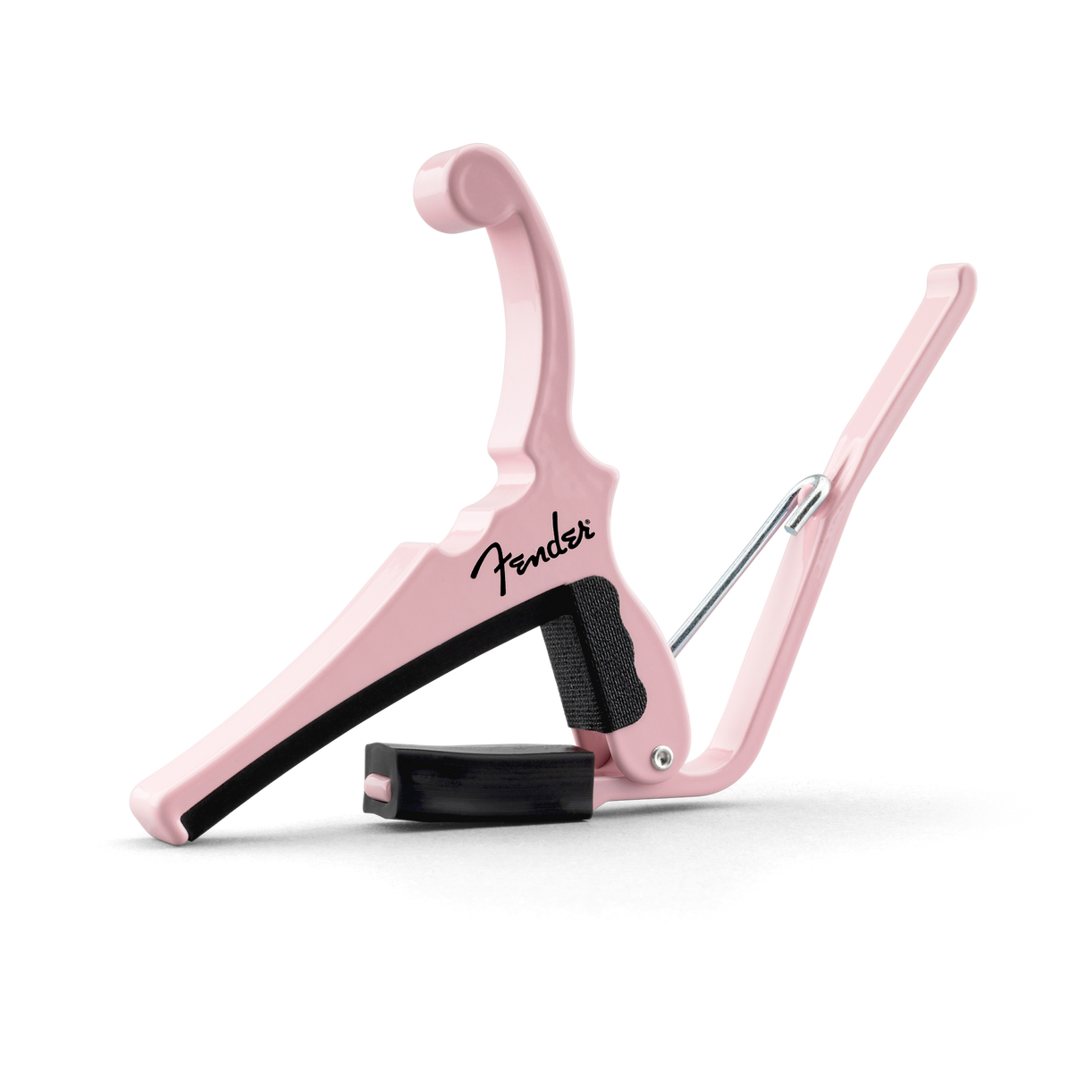 The image shows a Fender guitar capo in a stylish pink/shell pink color. It features a spring-loaded, curved clamp design with black padding to protect the guitar neck. Made of durable metal with a smooth finish, it has an ergonomic handle for easy use. This reliable capo evenly presses all strings, helping guitarists change keys while maintaining tuning and chord fingerings.