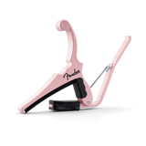 The image shows a Fender guitar capo in a stylish pink/shell pink color. It features a spring-loaded, curved clamp design with black padding to protect the guitar neck. Made of durable metal with a smooth finish, it has an ergonomic handle for easy use. This reliable capo evenly presses all strings, helping guitarists change keys while maintaining tuning and chord fingerings.