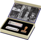 The image shows a commemorative set featuring a Hohner Marine Band harmonica, its original packaging, and a wooden stamp engraved with "SONNY TERRY." The elegant box lid displays vintage black-and-white photos from the 1940s to 1980s, documenting the history of blues music. This special edition honors blues harmonica legend Sonny Terry, combining a classic instrument with historical imagery for collectors.