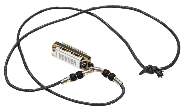 The image shows a Hohner brand harmonica necklace featuring a small, 10-hole diatonic harmonica mounted on an adjustable black braided cord. The harmonica is attached with a metal spring or coiled wire connector decorated with beads. This wearable design is popular among folk, blues, and street musicians, allowing hands-free play and easy access while performing with other instruments.