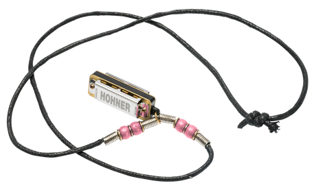 The image shows a Hohner harmonica necklace featuring a small, chrome-plated harmonica with gold reed plates on an adjustable black braided cord. The necklace includes pink beads and metal wire wrappings. Designed for easy, hands-free access, it’s popular among folk, blues, and country musicians. Hohner, a renowned German brand established in 1857, is known for high-quality harmonicas and accordions.