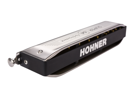 The image shows a Hohner harmonica with a black body featuring "HOHNER" in white letters, a chrome top plate with engraved text, and multiple front holes. This compact diatonic wind instrument is made by a renowned German brand since 1857, commonly used in blues, folk, country, and rock. Sound is produced as air flows through the holes, vibrating metal reeds inside.