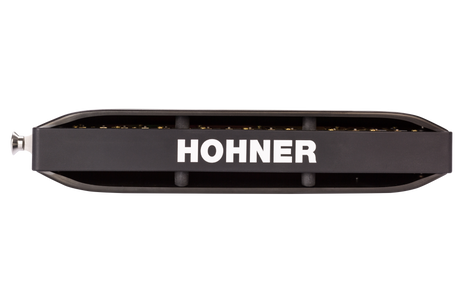 The image shows a Hohner harmonica, a well-known brand in the harmonica industry. It features a classic 10-hole diatonic design with a black comb and brass reed plates visible on top and bottom. The brand name "HOHNER" is prominently displayed in white on the body. Hohner, a German company since 1857, produces harmonicas used in many musical genres like blues, folk, and rock.