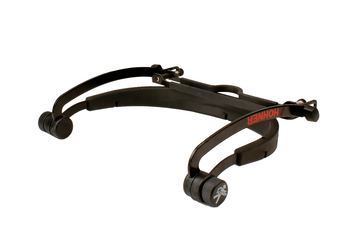 The image shows a black Hohner guitar capo with red branding. This spring-loaded, lever-style capo clamps across the fretboard to raise the pitch by pressing all strings simultaneously. Its curved design fits the guitar neck, and adjustable components allow pressure control. Capos help guitarists change keys easily, suit vocal ranges, and create varied tones, making this a professional-quality accessory for both casual and advanced players.