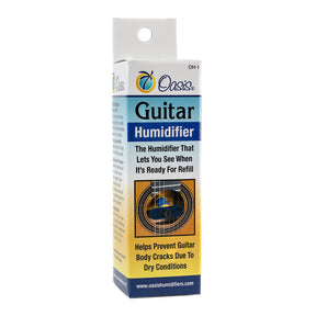 The image shows an Oasis guitar humidifier (model OH-1) designed to maintain proper humidity inside an acoustic guitar and prevent damage from dry conditions. The packaging features the Oasis palm tree logo, highlights a visual indicator for refilling, and depicts the humidifier placed in a guitar sound hole. This accessory helps protect the guitar’s wood from cracking or warping, especially in dry climates or heated indoor environments.