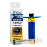 The image shows an Oasis Guitar Humidifier, a blue cylindrical device with a black cap and clear sight window, designed to fit inside an acoustic guitar’s sound hole. It helps maintain proper humidity (45-55%) to prevent wood cracking, fret buzz, and damage. The packaging highlights its role in protecting guitars from dry conditions. Oasis is a trusted brand for instrument humidifiers, essential for guitar care in dry or heated environments.