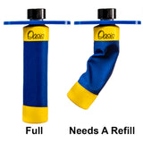 The image shows two Oasis musical instrument humidifier water bottles. The left bottle is full, while the right one is deflated, indicating it needs a refill. Both bottles feature blue and yellow branding with black caps. These humidifiers help maintain proper humidity in wooden instruments like guitars and violins, preventing damage from dry conditions by being placed inside cases or sound holes.