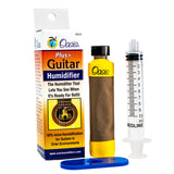 The image shows an Oasis Plus+ Guitar Humidifier set, including a colorful OH-5 packaging box, a cylindrical humidifier with a yellow cap and brown fabric sleeve, a 10ml syringe for refilling, and a blue stand. The box highlights the humidifier’s feature to indicate when it needs refilling and offers 50% more humidification to protect acoustic guitars from dryness and damage.
