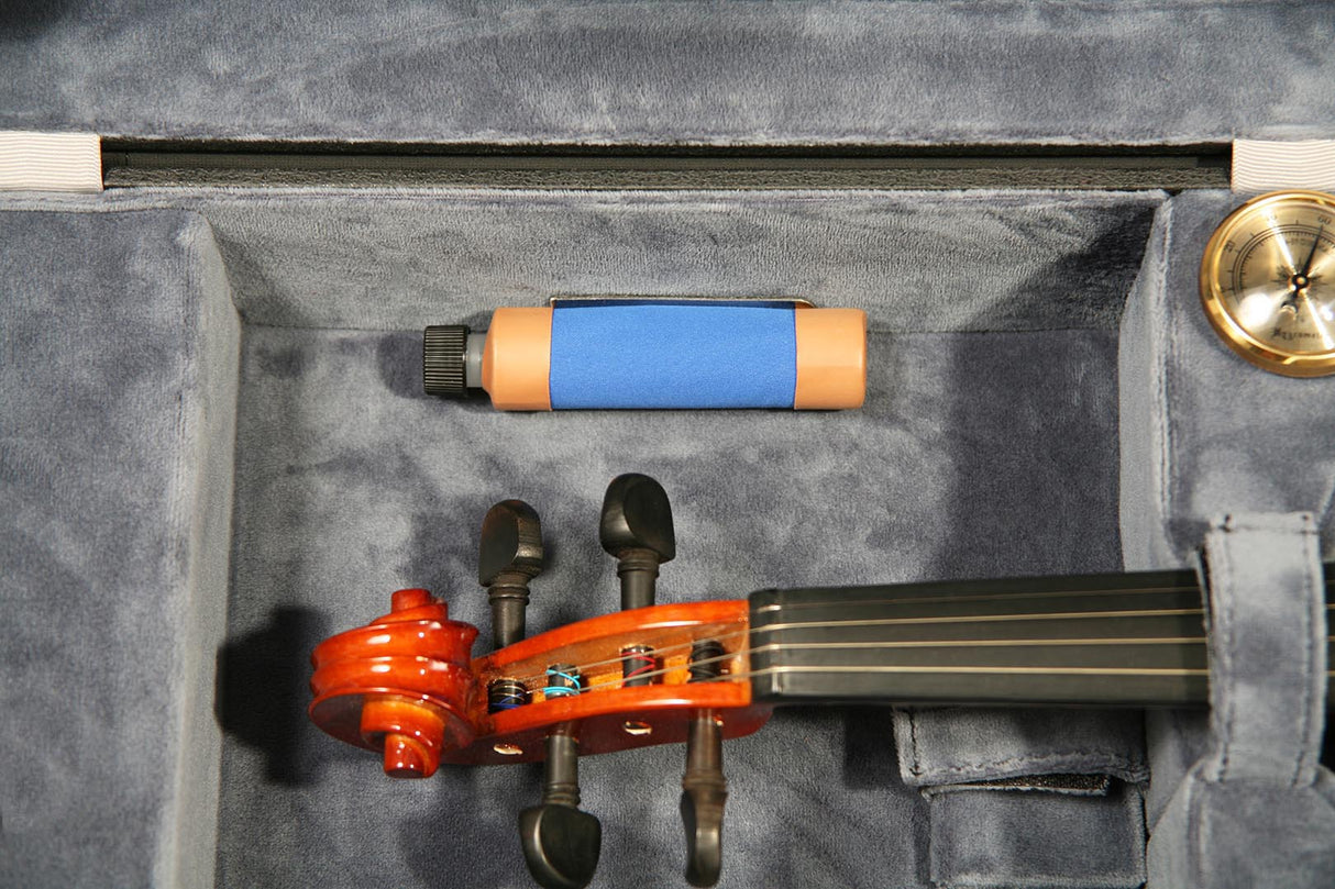 The image shows a violin with an orange-reddish body inside a gray foam-lined protective case. The strings and tuning pegs are visible. Above it lies a violin bow with a blue grip wrap, black handle, and orange/tan ends. In the case's upper right corner is a circular metallic object, likely rosin or a violin accessory. The case is neatly organized with essential items for playing and maintaining the violin.