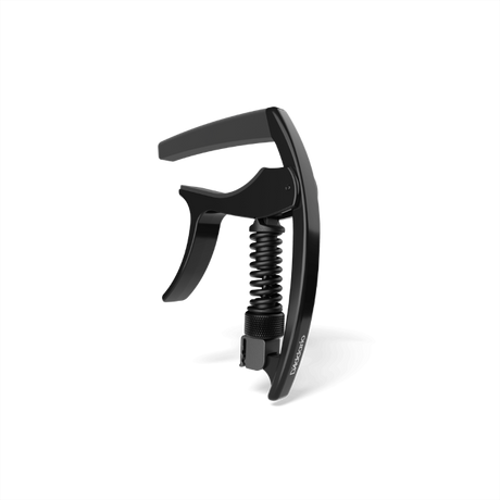 The image shows a black, spring-loaded clamp-style guitar capo with a curved mechanism, padded bar, and ergonomic handle for one-handed use. Made from metal and rubber or silicone, it features a sleek, modern design. This accessory clamps across the fretboard to raise string pitch, allowing guitarists to change keys easily while maintaining chord shapes. It appears to be a high-quality, professional-grade model.