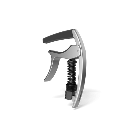 The image shows a guitar capo with a sleek silver metallic body and a black ergonomic handle. It features a visible black coiled spring in its spring-loaded, trigger-style release system for quick one-handed use. Designed to clamp the fretboard evenly, it raises string pitch without harming the guitar. Suitable for acoustic and electric guitars, this precision capo helps musicians easily change keys while maintaining chord fingerings.