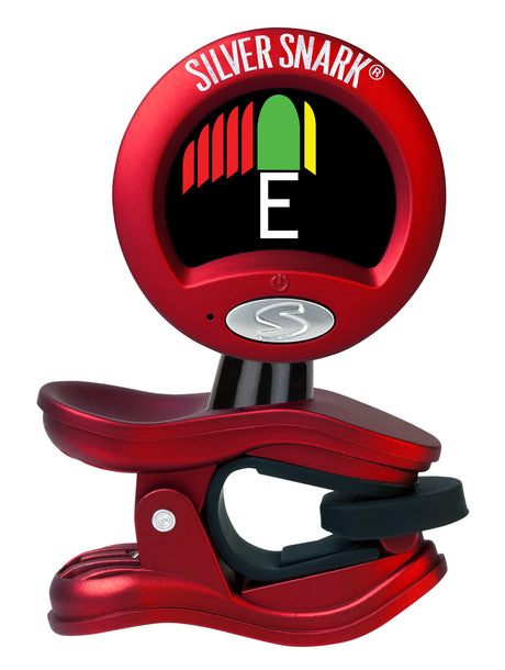 The image shows a red Snark clip-on chromatic guitar tuner with a circular display indicating the note "E" in white. It features a tuning meter with red bars for flat and green/yellow for in-tune/sharp, the "SILVER SNARK" brand name at the top, a clip for attaching to the instrument’s headstock, and an "S" logo button likely for power or mode selection. The tuner detects vibrations for accurate tuning in any environment.