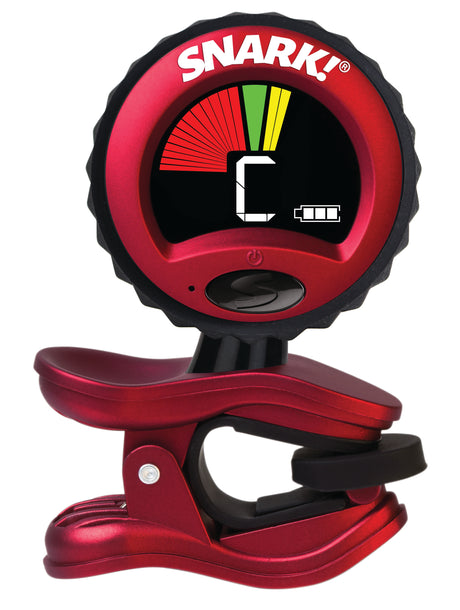The image shows a Snark clip-on guitar tuner with a red and black design and the "SNARK!" logo. It has a circular LCD display with a multicolored arc indicating tuning status (flat, in tune, sharp) and shows the note "C." A clip at the bottom attaches to the instrument's headstock, and a power button is visible on the front. This popular tuner picks up vibrations for accurate tuning of guitars and other stringed instruments.
