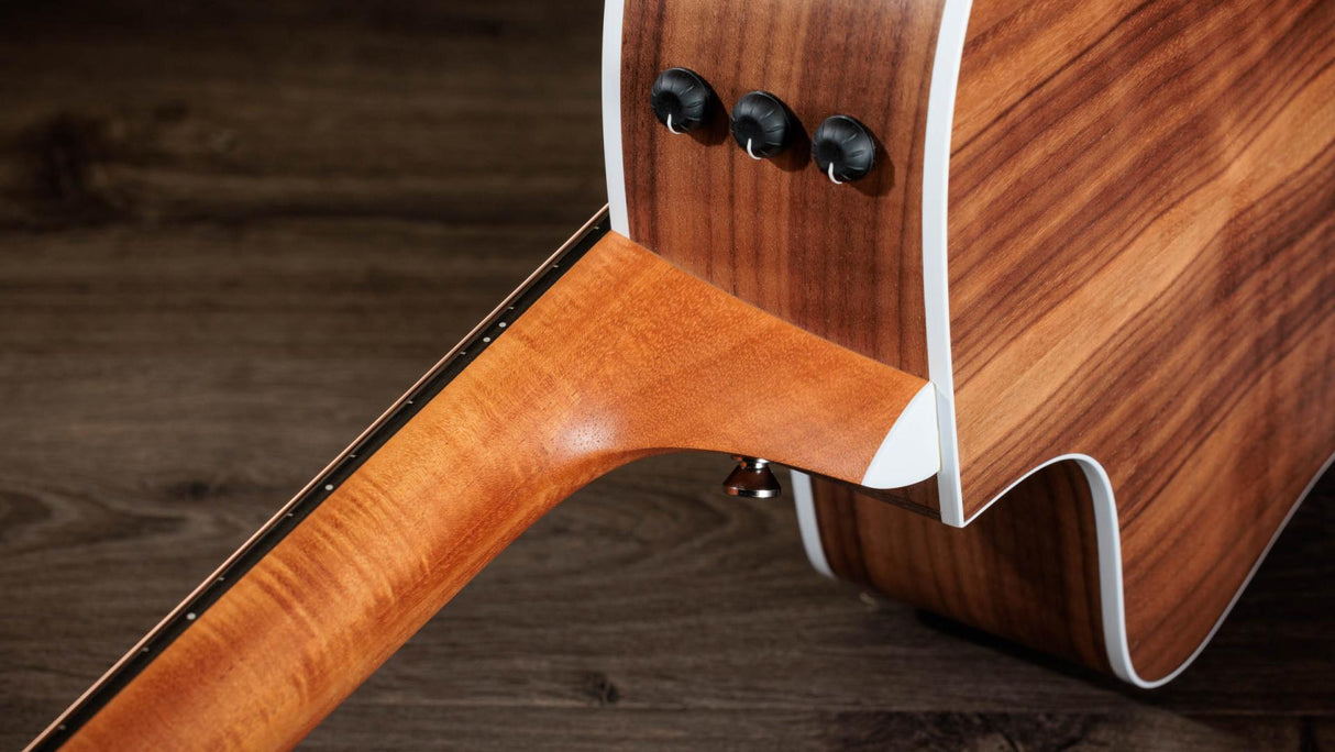 The image shows a high-quality wooden guitar stand or neck support featuring contrasting light and dark wood grains. It has three black tuning peg-style knobs on a curved, ergonomic vertical support. The polished, smooth finish and clean lines highlight professional craftsmanship. Functional hardware suggests adjustability. This premium accessory combines aesthetics and utility, ideal for acoustic or electric guitars and appreciated by serious musicians and collectors.