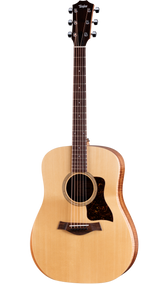 The image shows a Taylor acoustic steel-string guitar with a natural spruce top, darker wood back and sides, and a dreadnought body shape. It features chrome tuning pegs, a dark wood bridge, tortoiseshell pickguard, and a round soundhole with a decorative rosette. The neck has fret markers on dark wood. This well-crafted instrument reflects Taylor’s high-quality finish and design, suitable for both amateur and professional players.