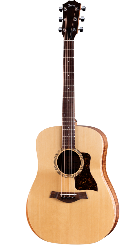 The image shows a Taylor acoustic steel-string guitar with a natural spruce top, darker wood back and sides, and a dreadnought body shape. It features chrome tuning pegs, a dark wood bridge, tortoiseshell pickguard, and a round soundhole with a decorative rosette. The neck has fret markers on dark wood. This well-crafted instrument reflects Taylor’s high-quality finish and design, suitable for both amateur and professional players.