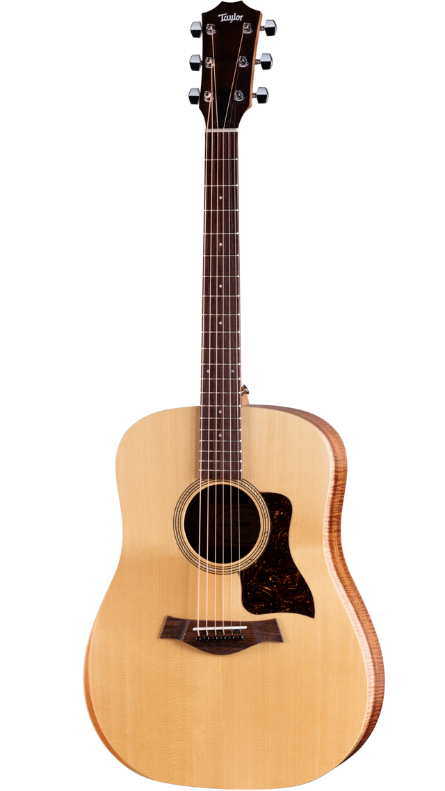 The image shows a Taylor acoustic steel-string guitar with a natural spruce top, darker wood back and sides, and a dreadnought body shape. It features chrome tuning pegs, a dark wood bridge, tortoiseshell pickguard, and a round soundhole with a decorative rosette. The neck has fret markers on dark wood. This well-crafted instrument reflects Taylor’s high-quality finish and design, suitable for both amateur and professional players.