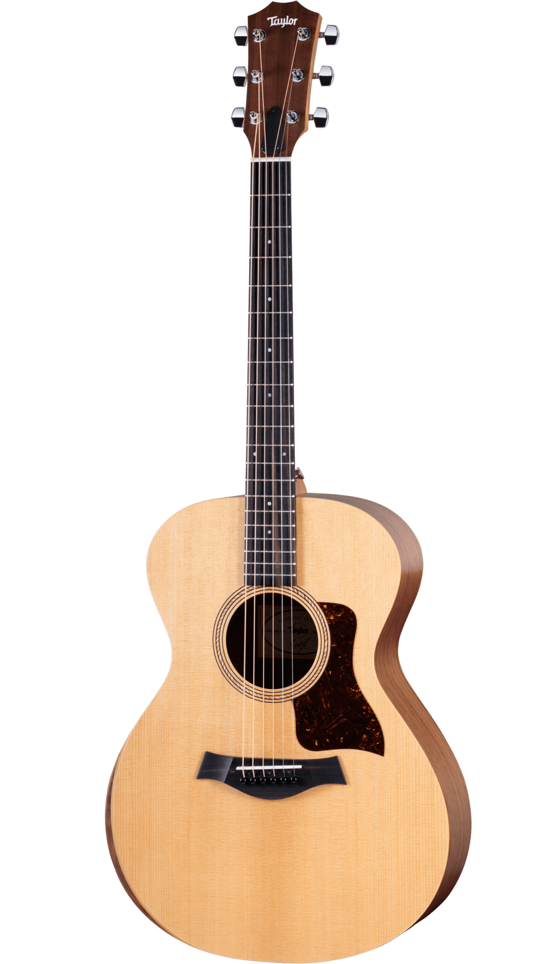 The image shows a Taylor acoustic guitar with a mid-size body, natural spruce top, and darker wood back and sides. It features a round soundhole with a decorative rosette, dark tortoiseshell pickguard, dark wood bridge with white pins, and a dark fretboard with dot markers. The headstock has Taylor’s signature shape with chrome tuners. This mid-to-upper range guitar is known for quality craftsmanship and balanced tone.