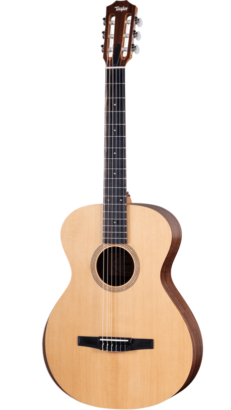 The image shows a Taylor classical guitar with a natural wood top and darker back and sides. It features a wide neck with a dark fretboard, six nylon strings, a slotted headstock with chrome tuners, and a black tie-block bridge. The round sound hole has a decorative rosette. This nylon-string acoustic guitar likely belongs to Taylor’s classical line, showcasing traditional design and craftsmanship.