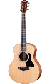 The image shows a Taylor steel-string acoustic guitar with a natural spruce or cedar top and darker mahogany or sapele back and sides. It features a mid-sized Grand Auditorium body, chrome tuning machines, a dark wood bridge with a compensated saddle, a round soundhole with a rosette, and a black pickguard. The natural finish highlights the wood grain, reflecting Taylor’s quality craftsmanship and versatile playability.