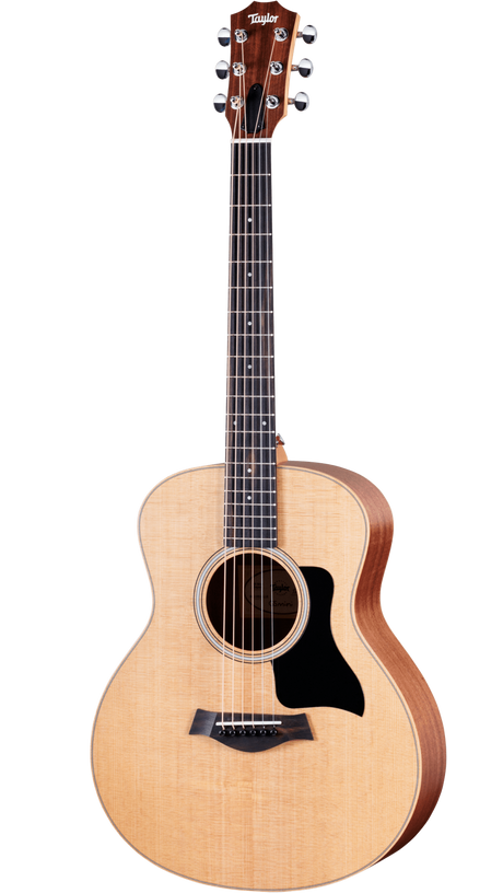 The image shows a Taylor steel-string acoustic guitar with a natural spruce or cedar top and darker mahogany or sapele back and sides. It features a mid-sized Grand Auditorium body, chrome tuning machines, a dark wood bridge with a compensated saddle, a round soundhole with a rosette, and a black pickguard. The natural finish highlights the wood grain, reflecting Taylor’s quality craftsmanship and versatile playability.