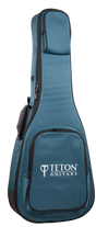 The image shows a teal and black padded gig bag from Teton Guitars, designed to carry and protect a full-size acoustic guitar. It features the "TETON GUITARS" logo on the front pocket, multiple zippered compartments, padded shoulder straps, and durable fabric construction, providing ample storage for accessories like picks, strings, and tuners.