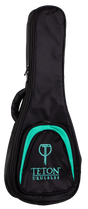 The image shows a black padded gig bag for a ukulele, made of durable fabric with protective padding. It features a full-length zipper, a carrying handle, and a front pocket branded with "TETON UKULELES" in turquoise text and a matching curved design. This lightweight, soft case offers portable protection for ukuleles and is made by the Teton brand.