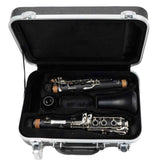 The image shows a disassembled clarinet in its protective hard case. The black woodwind parts with silver keys and tan cork joints are neatly arranged in custom-molded compartments lined with black foam. The case features metal latches and corner reinforcements. This typical setup helps protect the clarinet’s delicate keys and makes the instrument easier to transport and store.