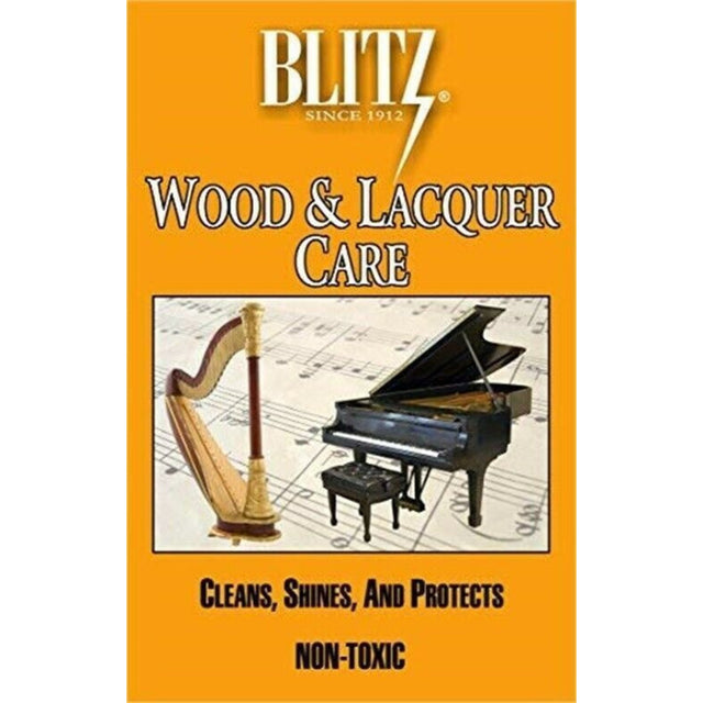 The image shows a product package for Blitz Wood & Lacquer Care, a musical instrument cleaner from a company since 1932. The package has an orange/yellow background with the Blitz logo, featuring a harp on the left and a grand piano on the right over sheet music. Text highlights "Cleans, Shines, and Protects" and "Non-Toxic." It is a care product for wooden and lacquered instruments like pianos and harps.