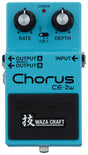 The image shows a Boss CE-2W Waza Craft Chorus guitar pedal, a modern reissue of the classic CE-2. It features two black knobs labeled RATE and DEPTH, a central toggle switch marked "S," a red CHECK LED, an input on the right, and two outputs for mono and stereo. The pedal has a turquoise body, Boss branding, and a Waza Craft logo with Japanese characters, offering vintage and modern chorus tones.