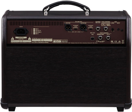 The image shows the back panel of a guitar amplifier featuring an AC power input with voltage selectors, various audio connections (DI/Line Out, XLR with ground lift, REC OUT, AUX IN), foot control ports, safety labels and certifications (FCC, CE), ventilation slots, and rugged construction with black tolex, metal corners, and a leather handle. It is a professional amp with global voltage settings for live and recording use.